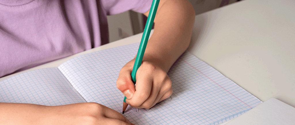 image of young left-handed learner writing on tilted graph paper for a post on left-handed writing